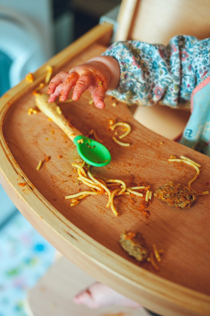 toddler's hand, a spoon and a messy table with food